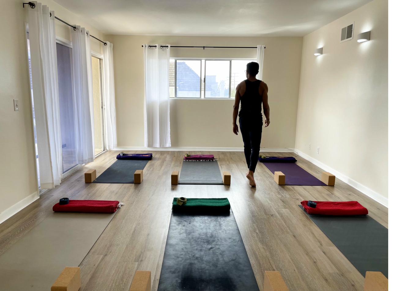 A group yoga class in a Brooklyn studio, students in a guided flow with attentive alignment.